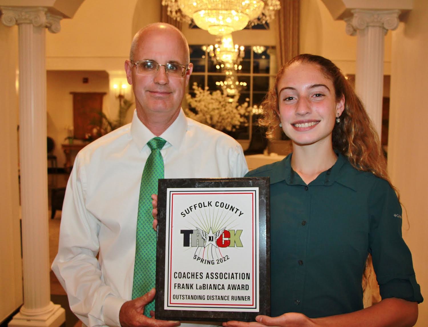 William Floyd High School freshman Zariel Macchia is pictured with head coach John Ryan receiving her second consecutive Coach Frank LaBianca Award as the most outstanding distance runner in Suffolk County.